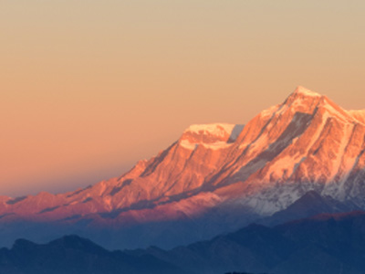 A large, snow-covered mountain at sunrise.