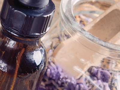 Close up of a bottle of essential oils and a jar filled with lavender flower buds