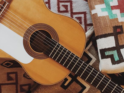 Close up of an acoustic guitar resting on patterned wool blankets