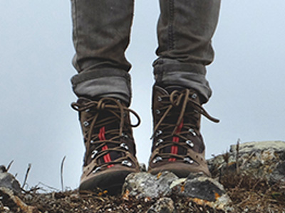 Closeup of a person wearing hiking boots on rugged terrain