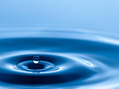A single droplet hitting a pool of water, causing gentle ripples