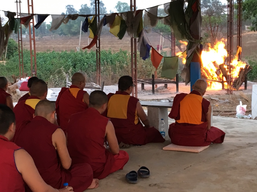 buddhist monks sitting in front of a pyre