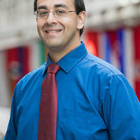 Andy Ramdular smiling at the camera in a blue button down shirt and red tie
