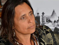 Winona LaDuke in a green shirt looking off into the distance