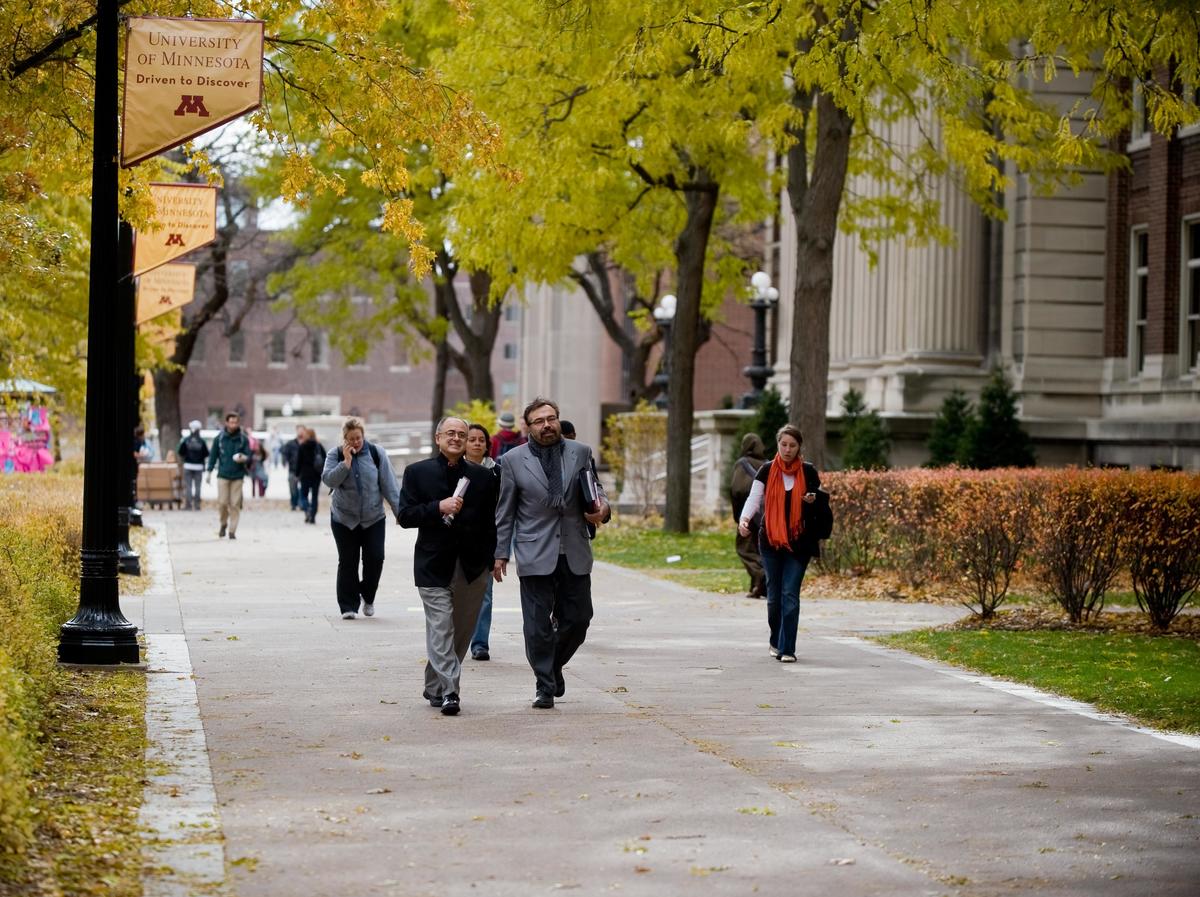 Students and professors walking along Northrop Mall in autumn
