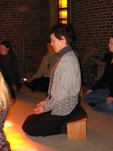Woman kneeling on a meditation bench. Her hands are in her lap and her eyes are closed.