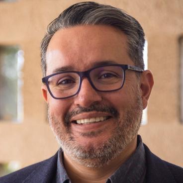 Eric Lopez Maya, a man wearing glasses smiling at the camera
