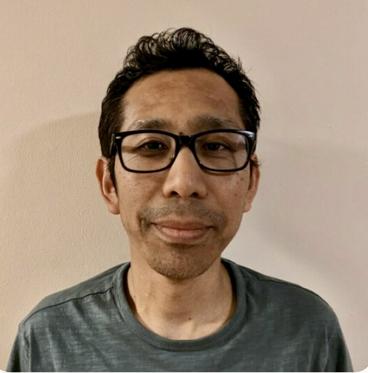 Tenzing sherap, an asian man wearing glasses and a grey shirt