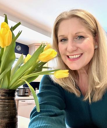 amy wheeler smiling beside a tulip in a vase on the table in front of her